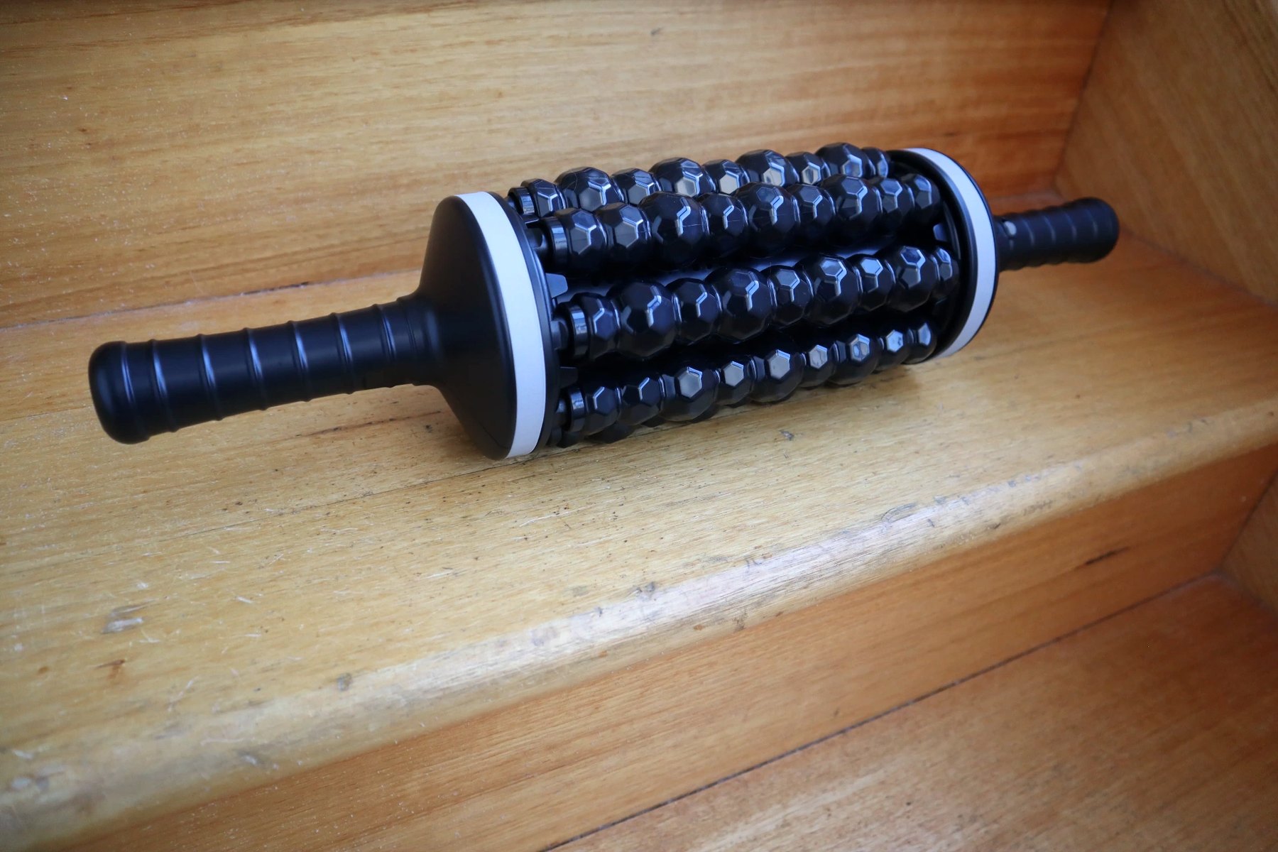 Rolling massager on a wooden step, three-quarter angle
